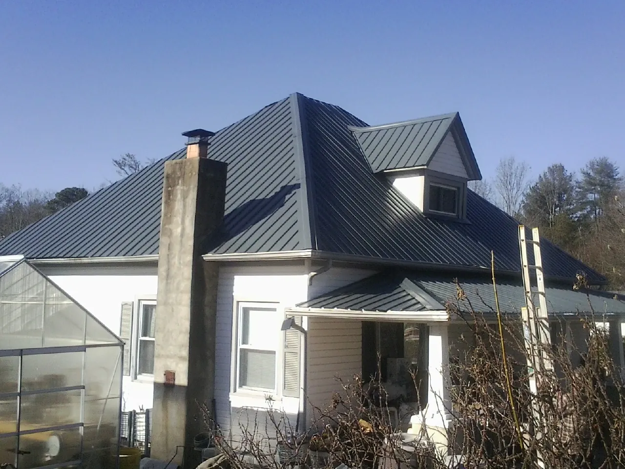 Dark blue standing seam metal roof on a white farmhouse with dormer — Slate & Tile Roof Repair by Roofing Brothers in Rootstown