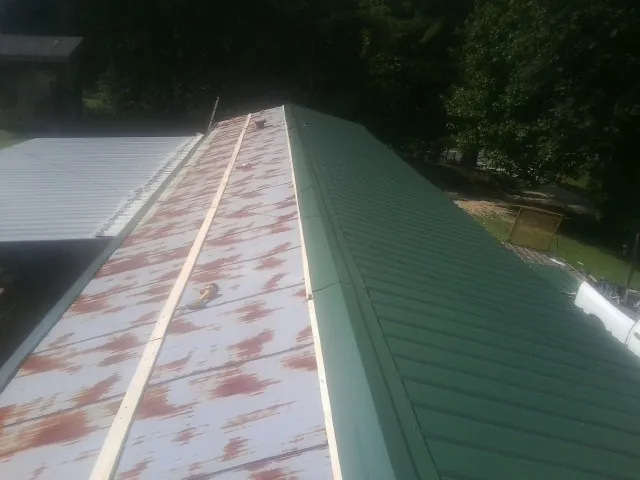 Old rusted panels beside newly installed green metal roofing — Wind Damage Roof Repair by Roofing Brothers in Rootstown