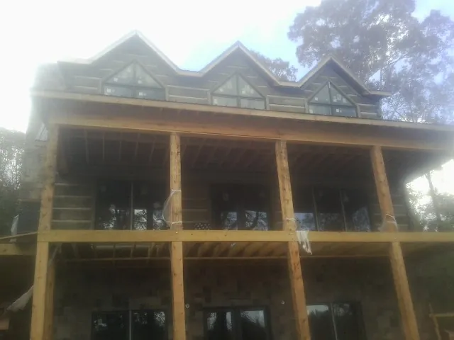 Dormers and porch framing on a large log home under construction — Roof Coating work by our crew in Rootstown