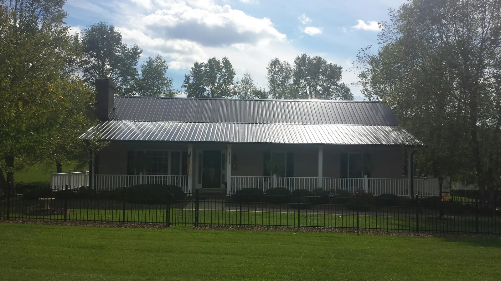 Gray metal roof on a brick ranch with a full width front porch — Gutter Guard Installation work by our crew in Rootstown
